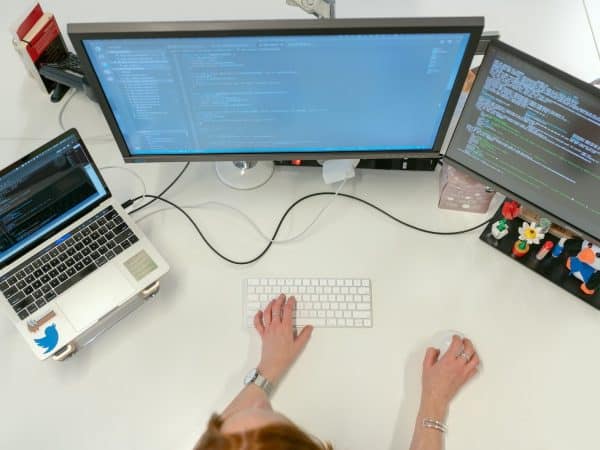 person using macbook pro on white table